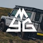 MyGrenadier.com Mountain Logo over Scottish White INEOS Grenadier driving off-road.